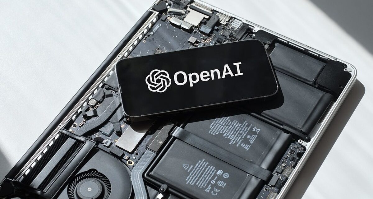 Phone displaying the OpenAI logo on exposed laptop components