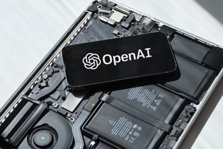 Phone displaying the OpenAI logo on exposed laptop components